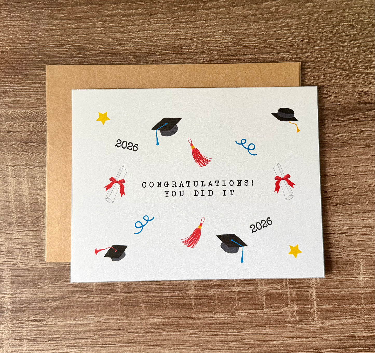 Graduation-themed card with colorful illustrations on a wooden surface